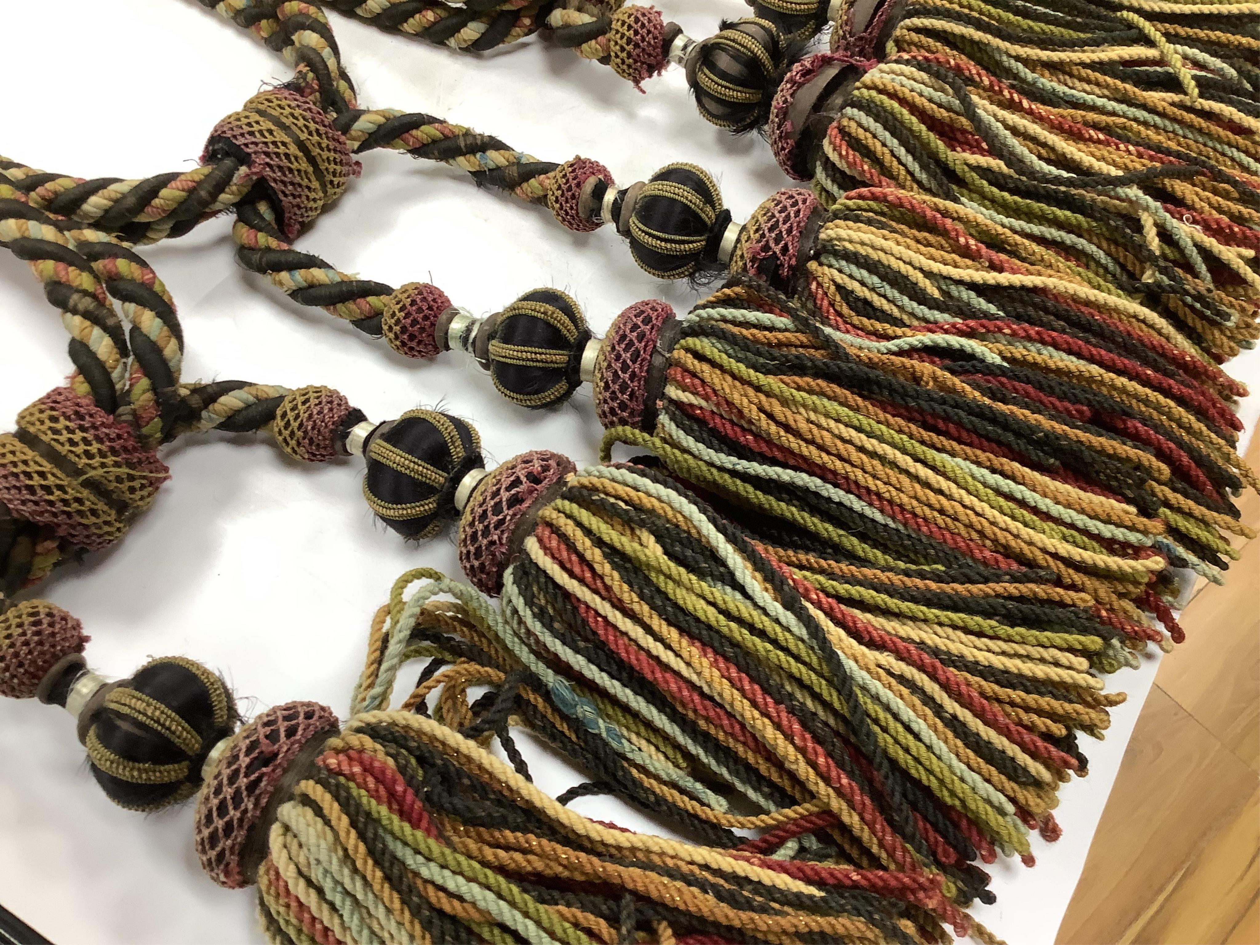 Four pairs of late 19th early 20th century corded and tasseled black and multicoloured tie backs. 69 cm long. Condition - all worn from use and age, one tassel needs repair.